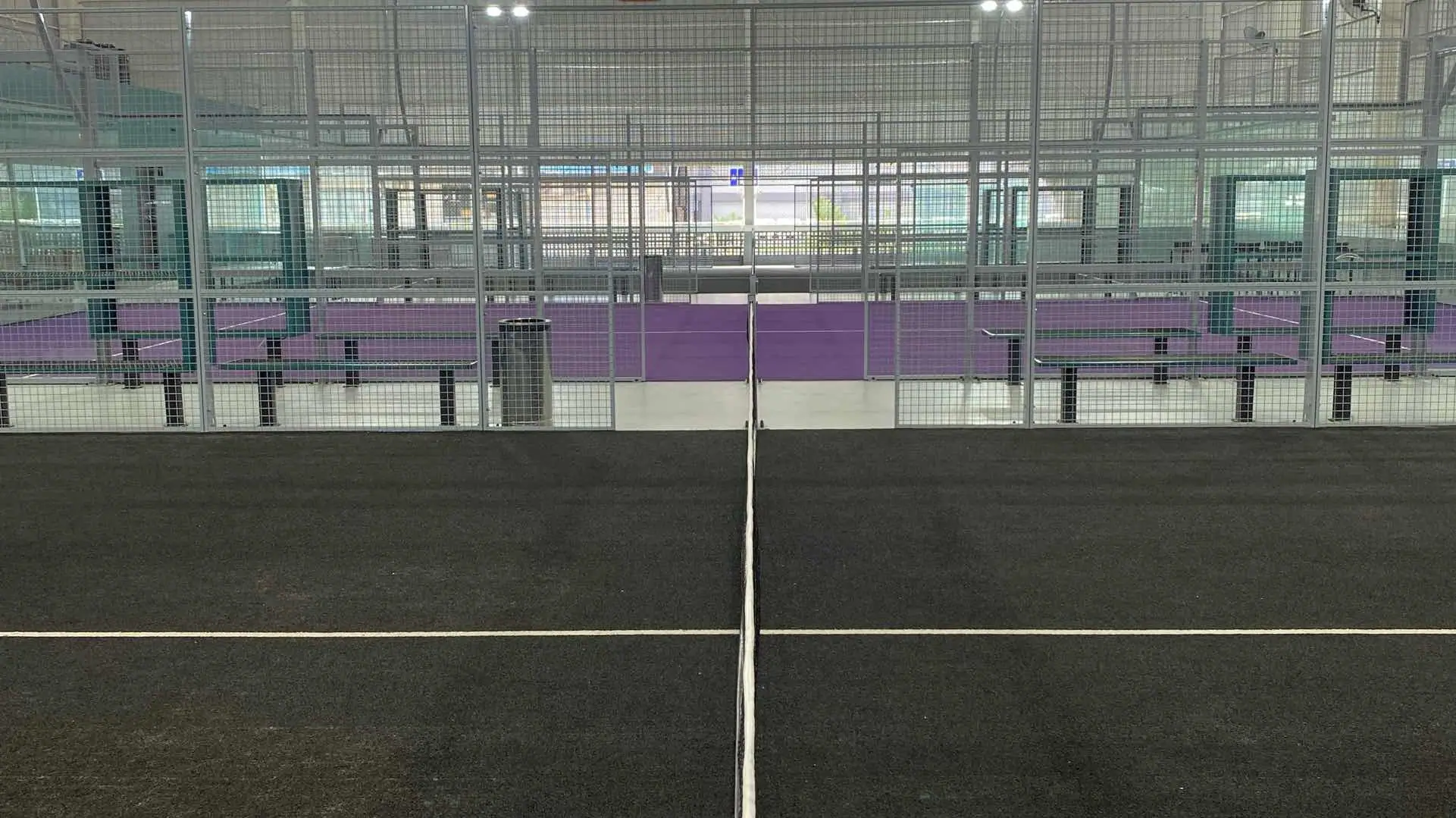 Black court surface with violet walls beyond the glass