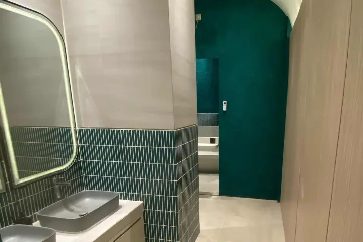 Bathroom with lit mirror and green tiles